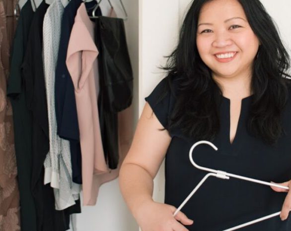 KonMari Consultant Helen Youn stands before a closet holding a hanger.