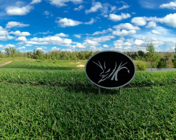 The Blue Devil Golf Course sign in a field on a sunny day.