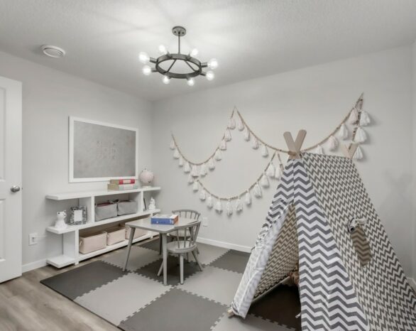 A grey room with a child-size tent, table, chair, and shelving.