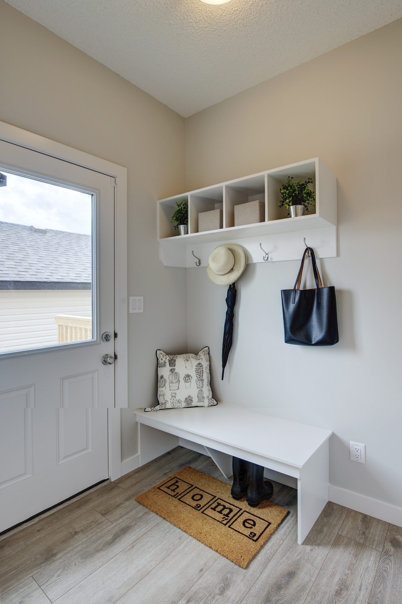 The entryway of a home with a white bench and coat hooks.