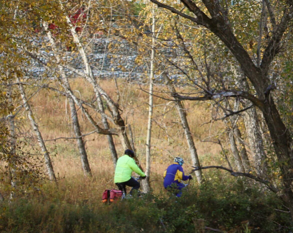 Two people bike through Fish Creek Park in autumn.