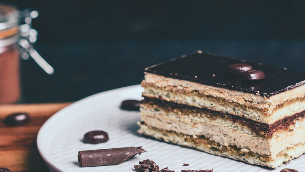 opera cake with chocolate and coffee bean decorations on a plate