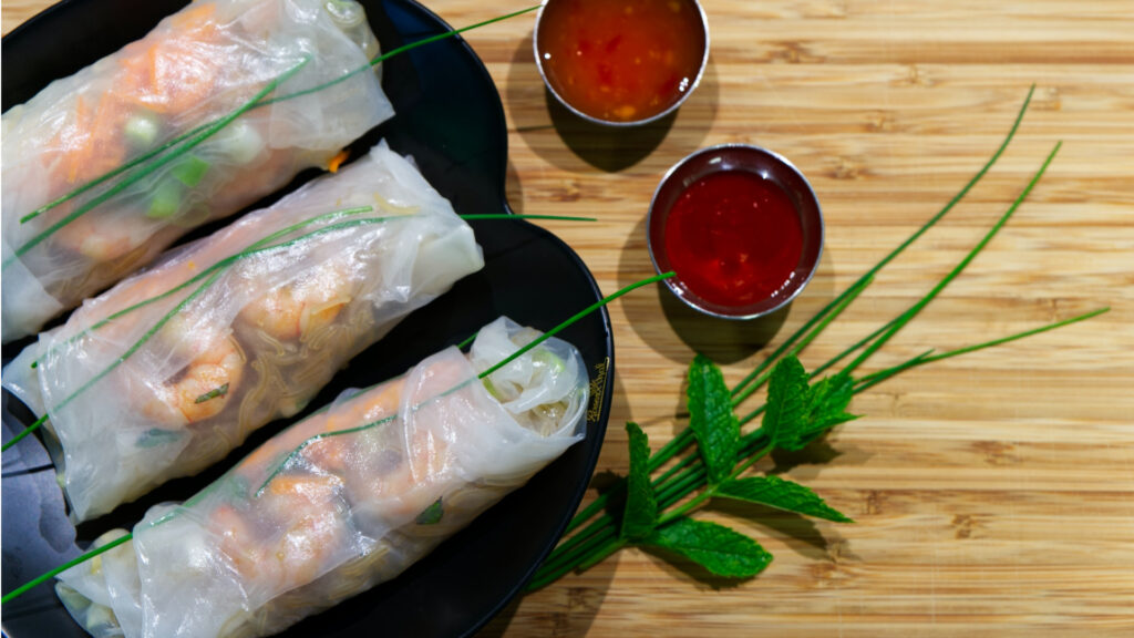 shrimp salad rolls on a plate with two chili dipping sauces