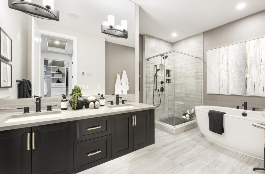 master bathroom with dark cabinetry, walk in shower with glass doors, and large soaker tub