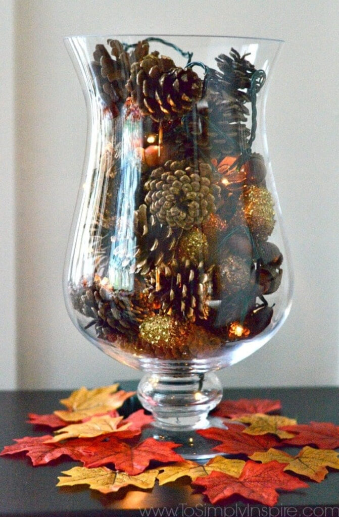glass vase filled with pinecones and fairy lights